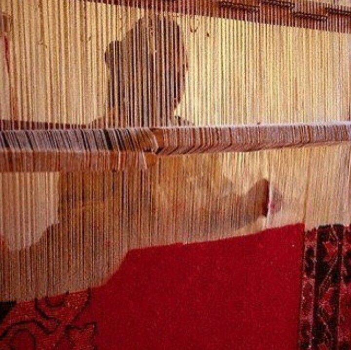 Artesana tejiendo alfombra tras telar